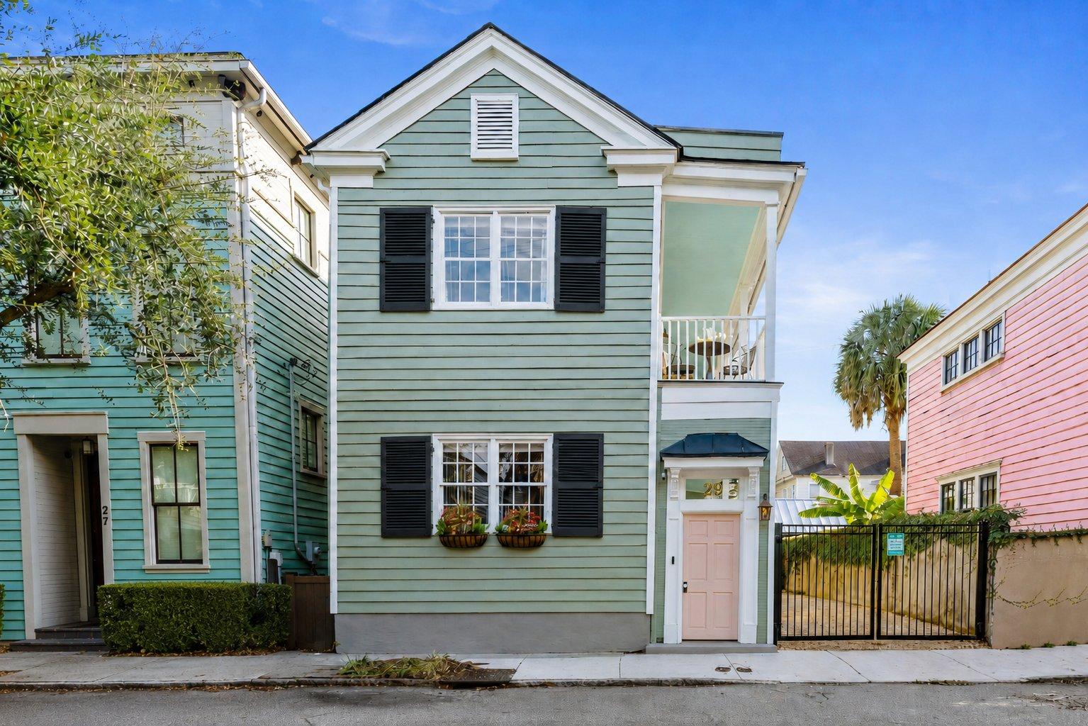 Breezy Palm, a sage green Charleston single house with a pink door